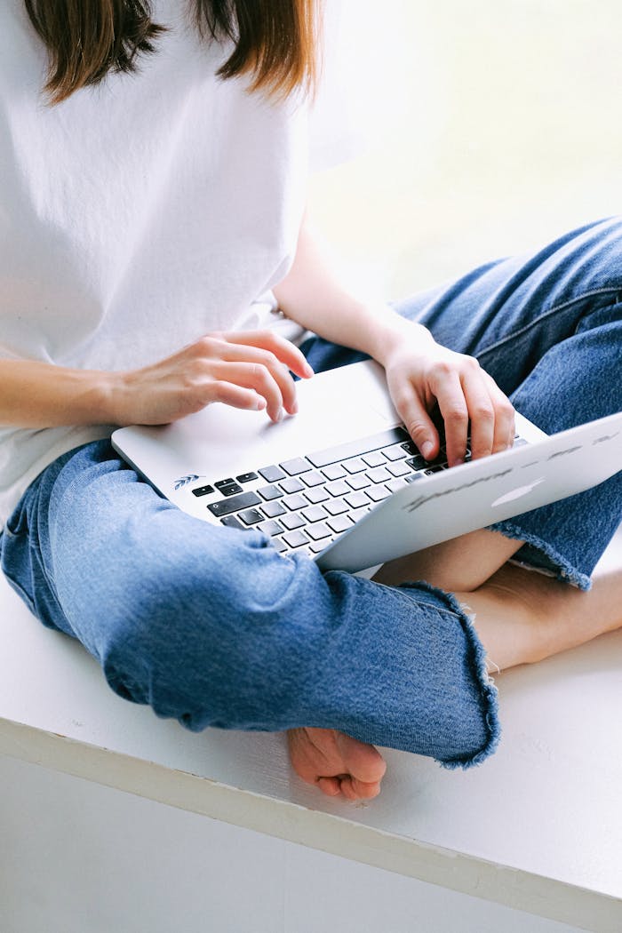 Crafting Captivating Headlines: Your awesome post title goes here Woman sitting cross-legged in casual jeans working on a laptop indoors.