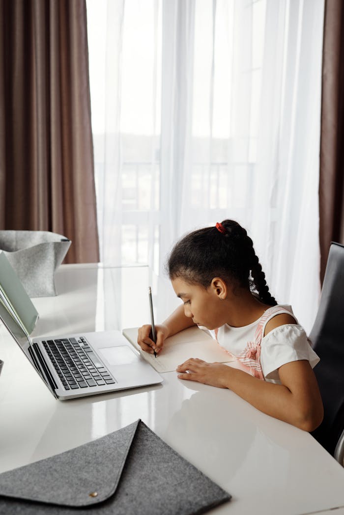Mastering the First Impression: Your intriguing post title goes here A young girl focuses on her studies at home using a laptop, emphasizing online learning.
