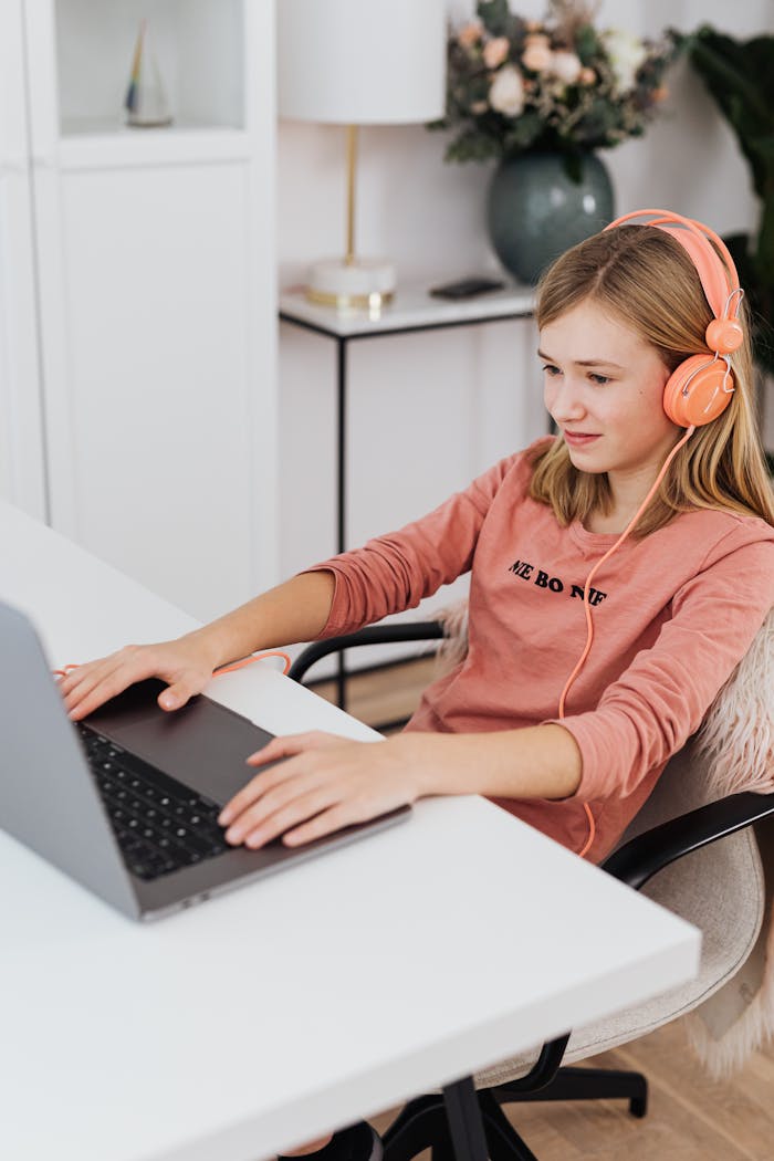 The Art of Drawing Readers In: Your attractive post title goes here A teenage girl wearing headphones and using a laptop at home. Cozy indoor setup with casual attire.